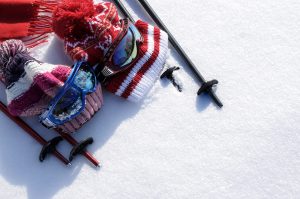 2 bonnets avec lunettes de ski et bâton de ski sur fond de neige