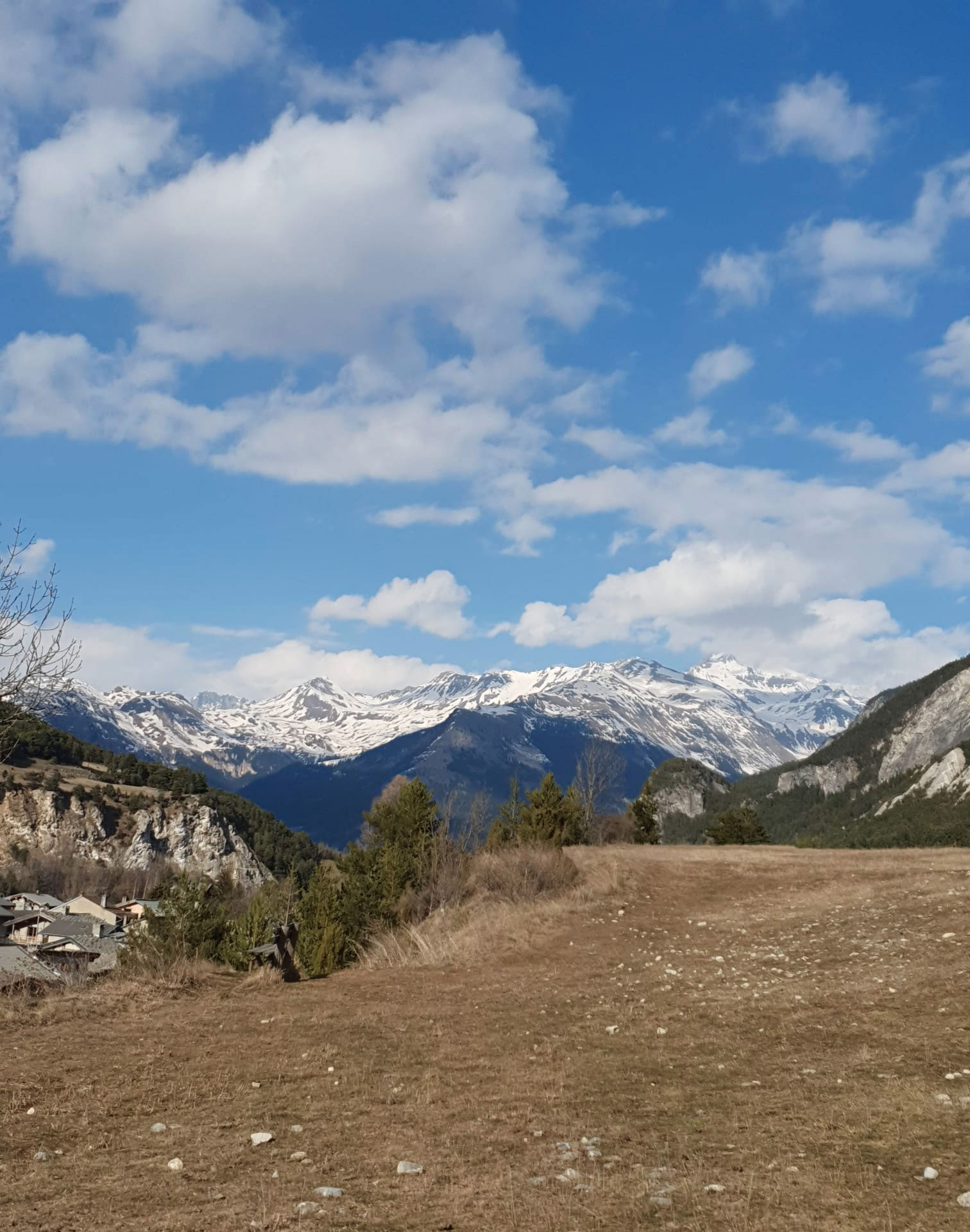 Paysage au loin les montagnes enneigées, en contrebas à gauche village de montagne - Vue d'un plateau